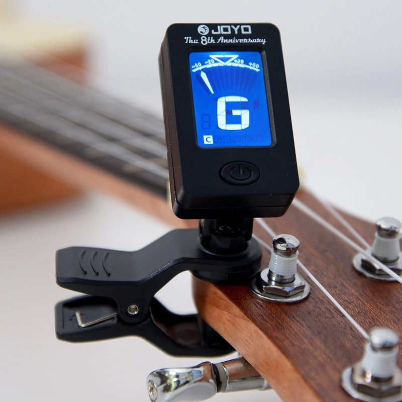 A picture of a digital tuner on a guitar picking up the G string